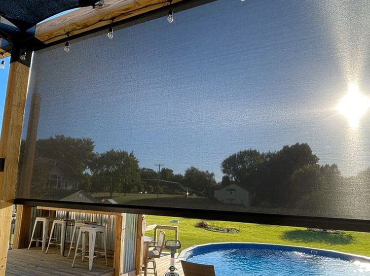 Exterior solar shade with cable guide system mounted on large window, featuring bar seating and pool view