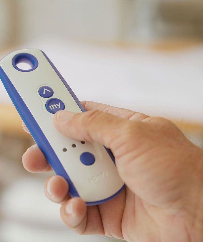 Hand holding remote control for motorized screen operation