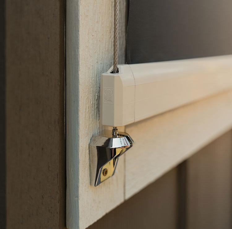 Close-up of white cable guide anchor point and tensioning system installed on exterior window frame
