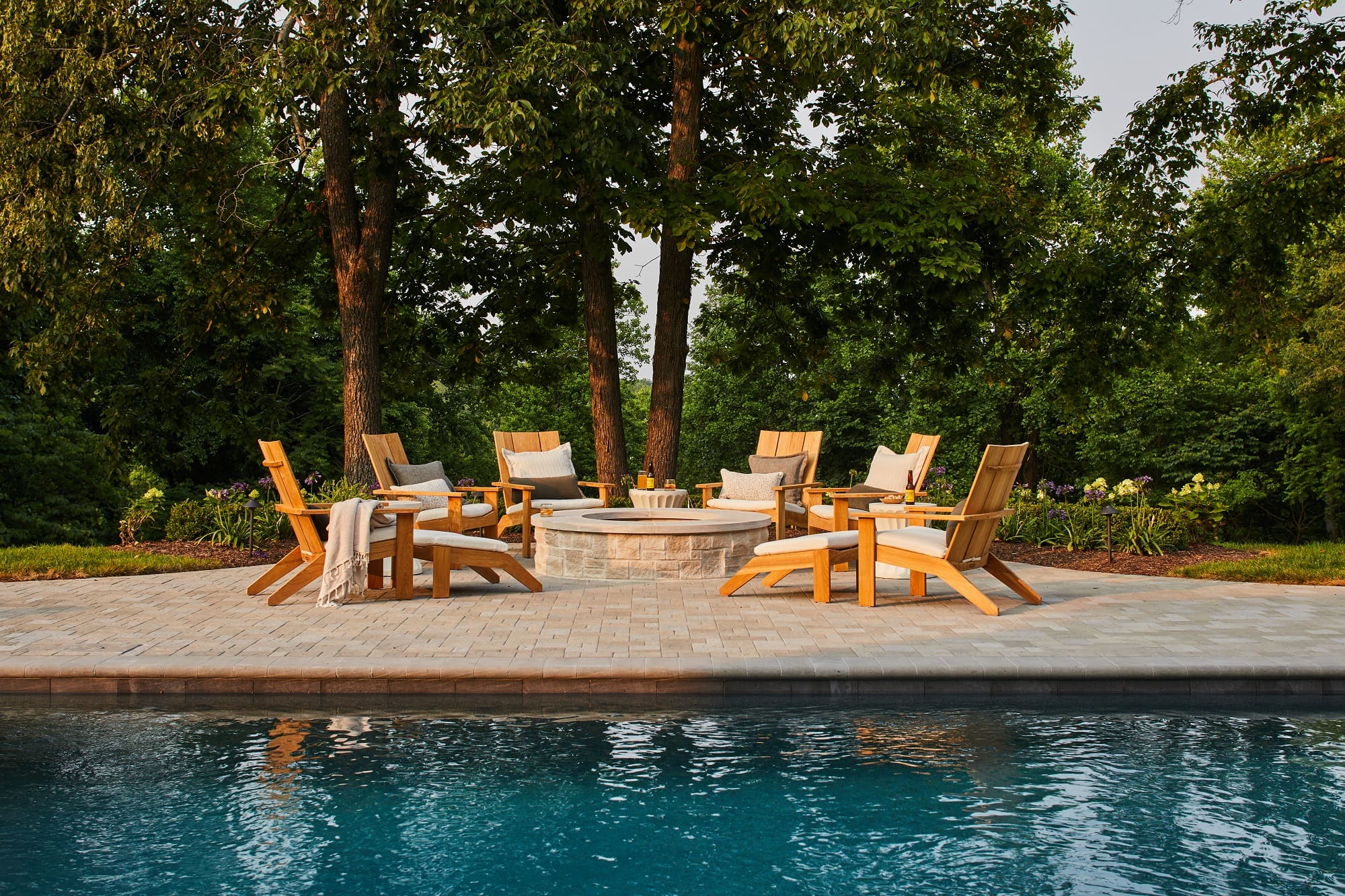 A serene pool area featuring lounge chairs and a cozy fire pit